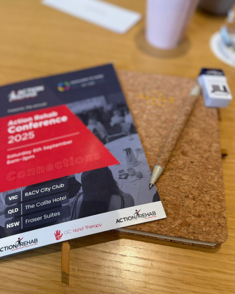 Conference program booklet and notepad displayed at the Shoulder to Hand Alliance Hand Therapy Conference 2025.
